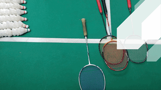 Green badminton court with white shuttle cocks and four badminton racket laying on the court. Badminton and other various racket sports are available at Newton Abbot Leisure Centre, Broadmeadow Sports Centre and Dawlish Leisure Centre.