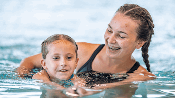 Swim teacher teaching a young girl in the swimming pool.