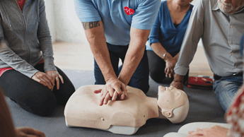 First Aid at Work course taking place with CPR on a CPR dummy.