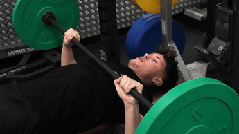 Male lifting weights in a gym environment.