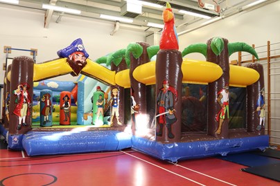 Pirate bouncy castle with slide and obstacle course challenges.