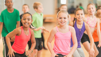 Two children with colourful tops on participating in an exercise class.